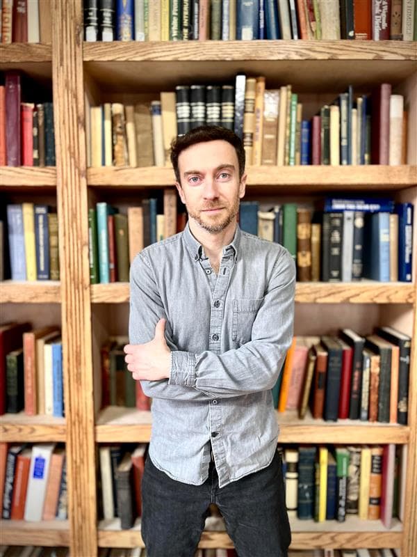 Eliot Stein standing in front of bookshelves
